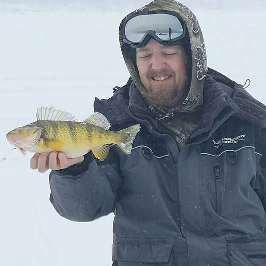 Angler in Boreas cold weather fishing gear on frozen lake with ice fishing sled, demonstrating organized gear accessibility in extreme cold