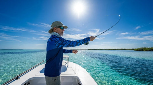 angler on a flats boat casting in harsh midday sun, wearing a long-sleeve UPF fishing shirt, bright sky and blue water behind him