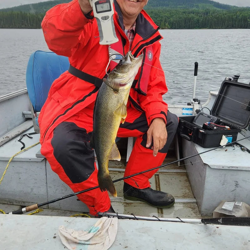 Angler in red rain suit holding walleye on boat during overcast conditions