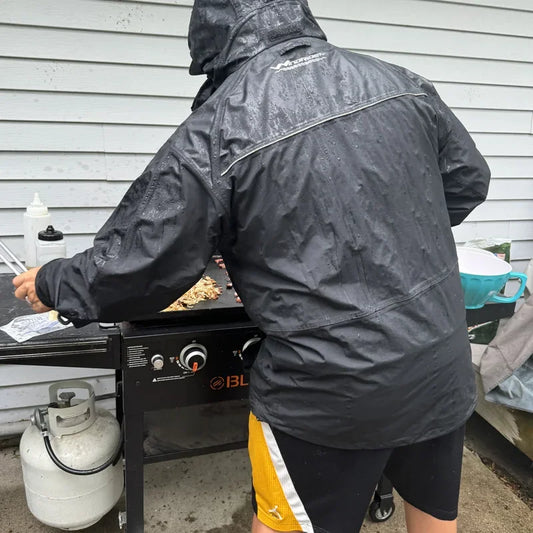 Angler in red WindRider rain jacket holding large lingcod on fishing boat under overcast skies