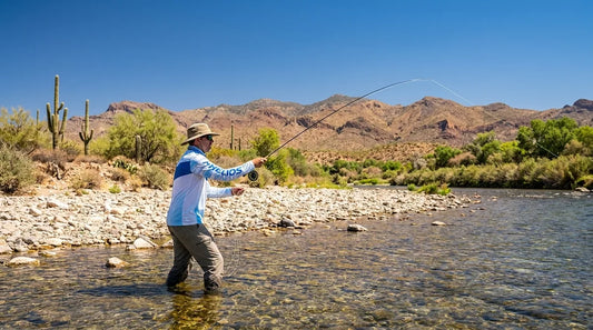 fly fisherman wading the Salt River in Arizona, bright summer midday sun, low desert mountains in background, clear shallow water, angler in long-sleeve UPF shirt casting a fly rod